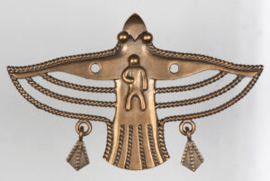 Kultainen lintuaiheinen koru, jossa on metsästäjän kuva linnun keskellä.